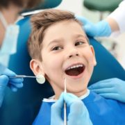 Young boy smiles as he gets dental work done.