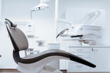 A modern dentist chair sits unoccupied in a white colored dentist exam room.