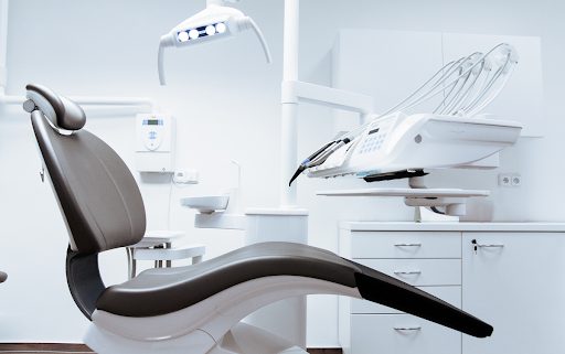 A modern dentist chair sits unoccupied in a white colored dentist exam room.