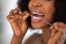 A woman uses floss to clean her brilliant smile.